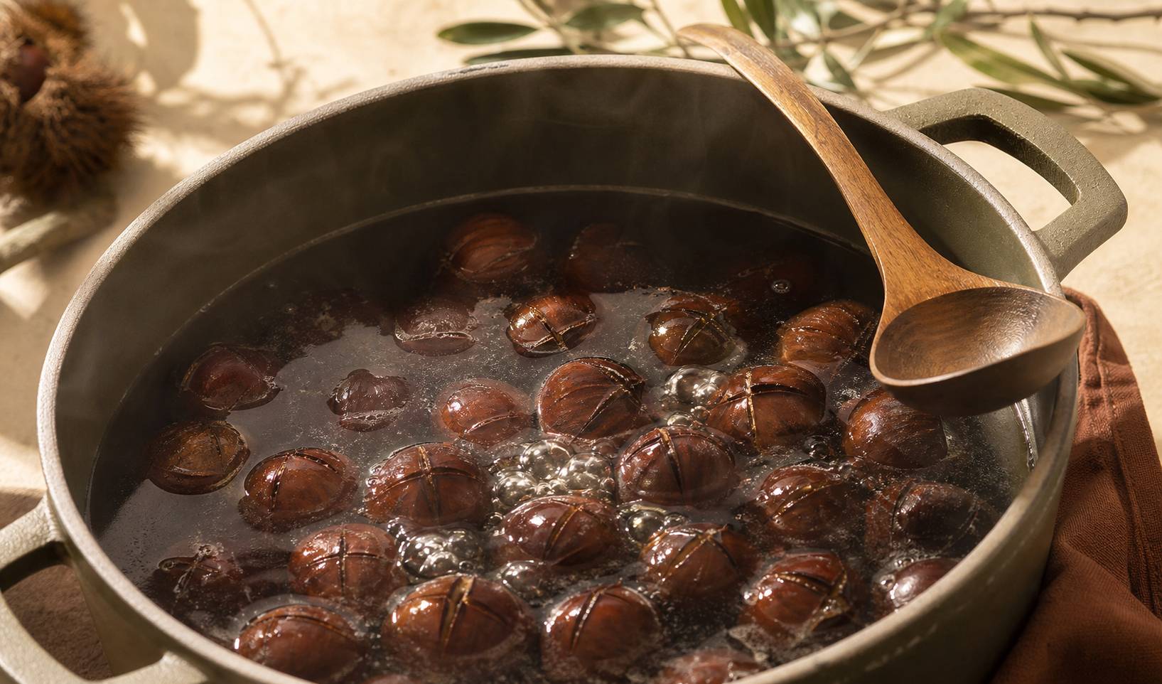 Gros plan de châtaignes incisées en croix dans une casserole frémissante avec cuillère en bois et vapeur légère